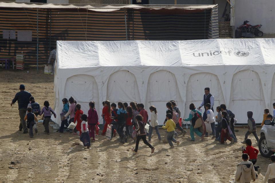 Syrian refugee children walk together to receive their polio vaccine at a Syrian refugee camp near the Bekaa Valley