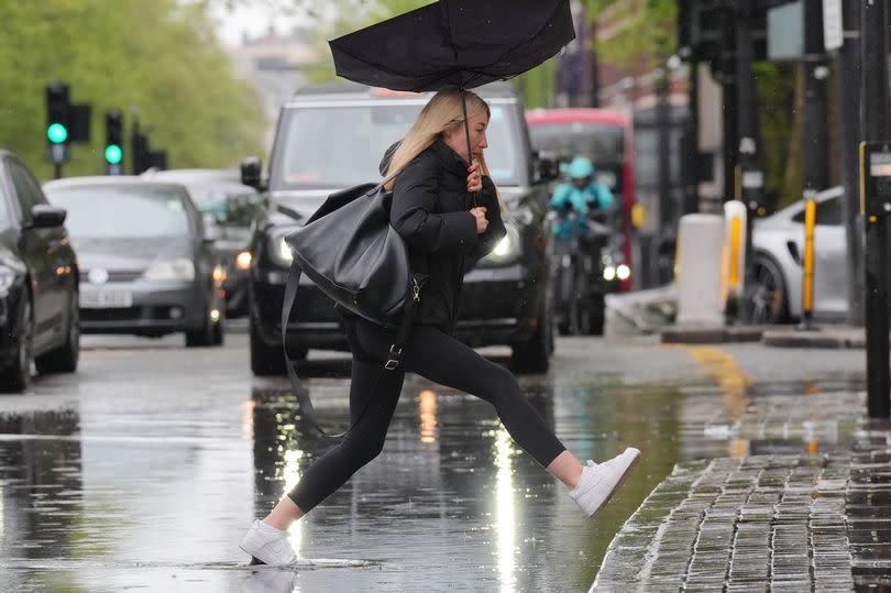 Pedestrian jumps over a puddle of rainwater in central London