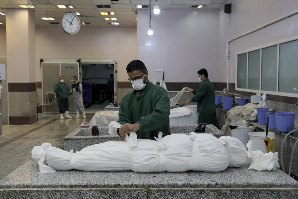 A cemetery worker prepares the body of a man who died from COVID-19, in a morgue at the Behesht-e-Zahra cemetery on the outskirts of the Iranian capital, Tehran, Iran, Sunday, Nov. 1, 2020. The cemetery is struggling to keep up with the coronavirus pandemic ravaging Iran, with double the usual number of bodies arriving each day and grave diggers excavating thousands of new plots. (AP Photo/Ebrahim Noroozi)