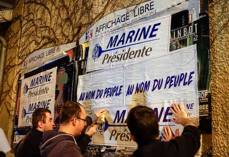 FILE PHOTO: Members of the National Front youths put up posters of Marine Le Pen, French National Front (FN) political party leader and candidate for the French 2017 presidential election, ahead of a 2-day FN political rally to launch the presidential campaign in Lyon, France, February 2, 2017. REUTERS/Robert Pratta/File Photo