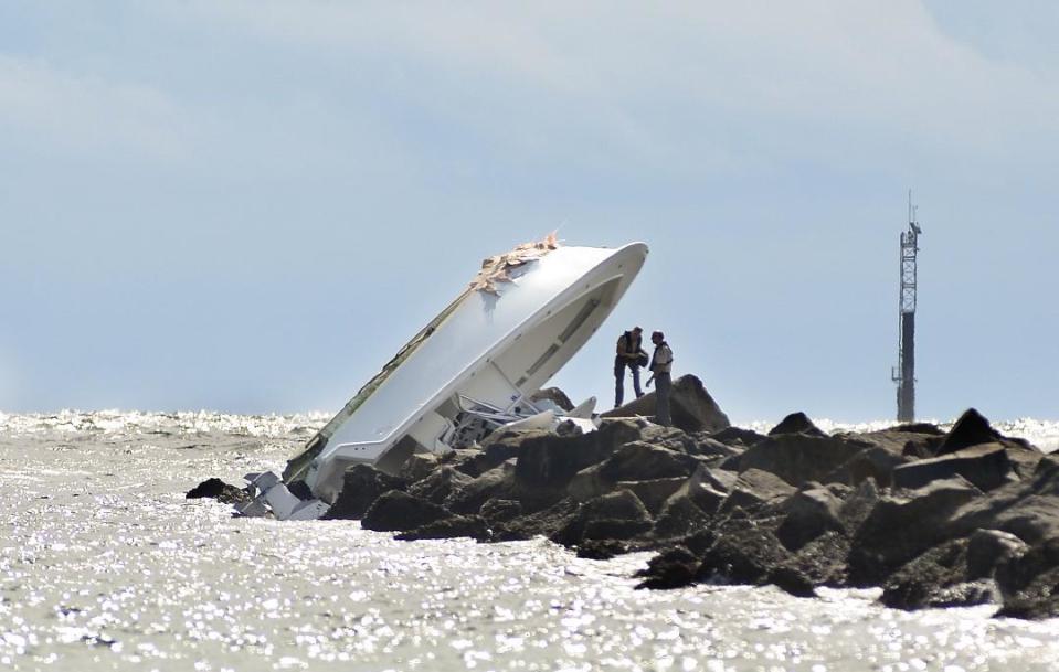 FILE - In this Sept. 25, 2016, file photo, investigators inspect an overturned boat as it rests on a jetty after a crash off Miami Beach, Fla. Miami Marlins pitcher Jose Fernandez was the "probable" operator of a speeding boat that crashed into a Miami Beach jetty on Sept. 25, 2016, killing the star baseball star and two other men, according to a report issued Thursday, March 16, 2017, by the Florida Fish and Wildlife Conservation Commission, which investigated the accident. (AP Photo/Gaston De Cardenas, File)