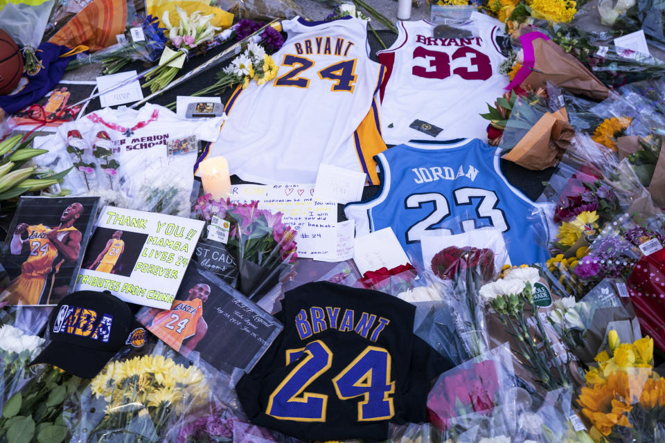 Flowers, jerseys and imagery is left in remembrance to Kobe Bryant at a small memorial at the entrance of the Bryant Gymnasium at Lower Merion High School, Monday, Jan. 27, 2020, in Wynnewood, PA. (AP Photo/Chris Szagola)