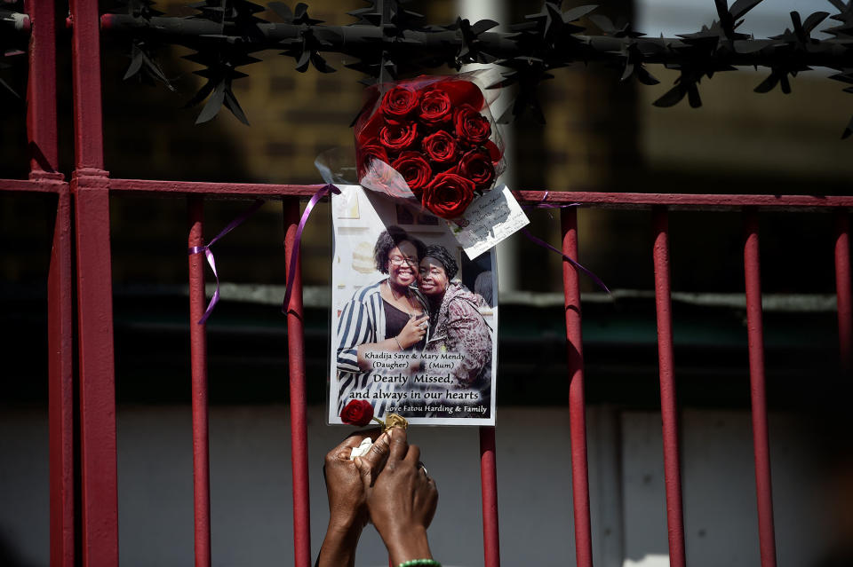 <p>A woman attaches a rose to a poster of a person missing in the Grenfell apartment tower block fire in North Kensington, London, Britain, June 17, 2017. (Hannah McKay/Reuters) </p>