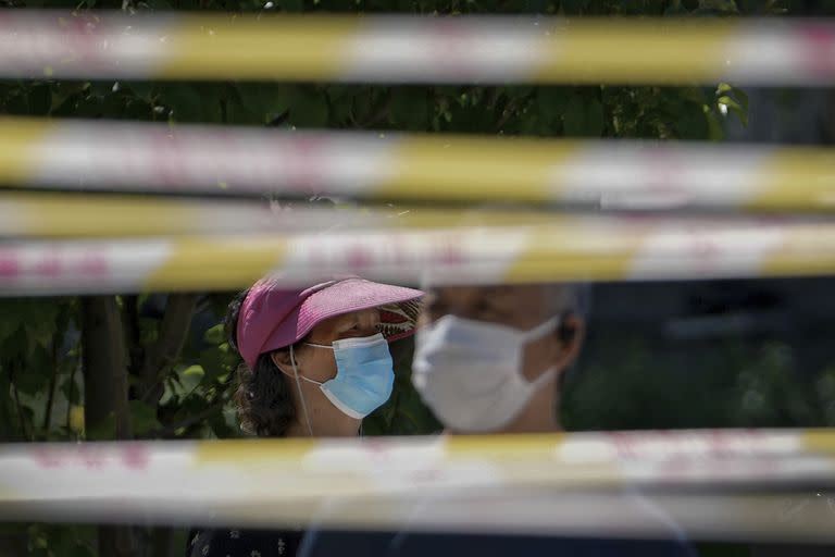 Personas con mascarillas hacen fila detrás de barricadas para recibir pruebas de COVID en Pekín, 15 de mayo de 2022