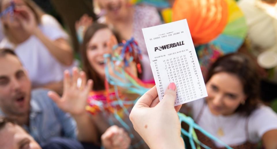 Aussie player holds winning Powerball ticket up during celebration