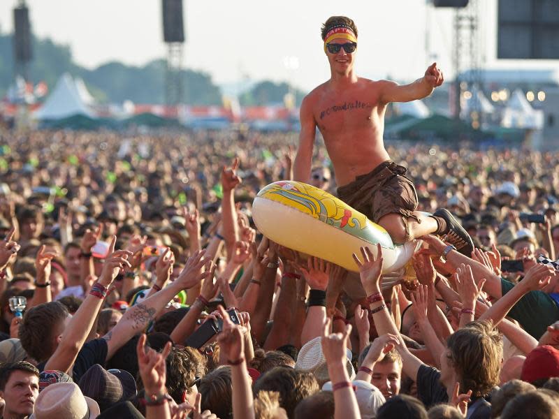 Bad in der Menge: Ein Festivalbesucher wird beim Rockfestival «Rock am Ring» auf dem Nürburgring in einem Schlauchboot über die Köpfe der Fans getragen. Foto: Thomas Frey