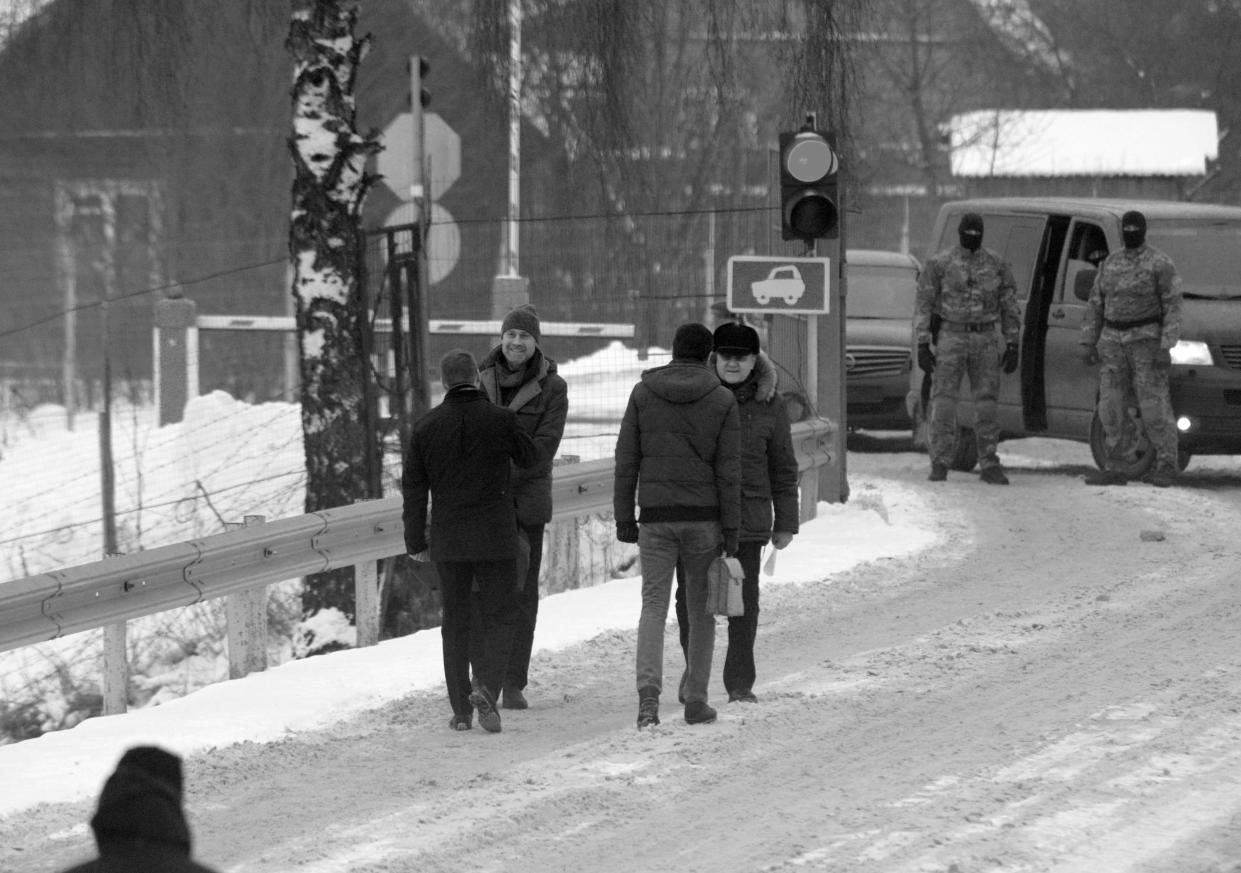 Estonian Raivo Susi and Russian Artem Zinchenko with their handlers during a prisoner exchange on a snowy bridge.
