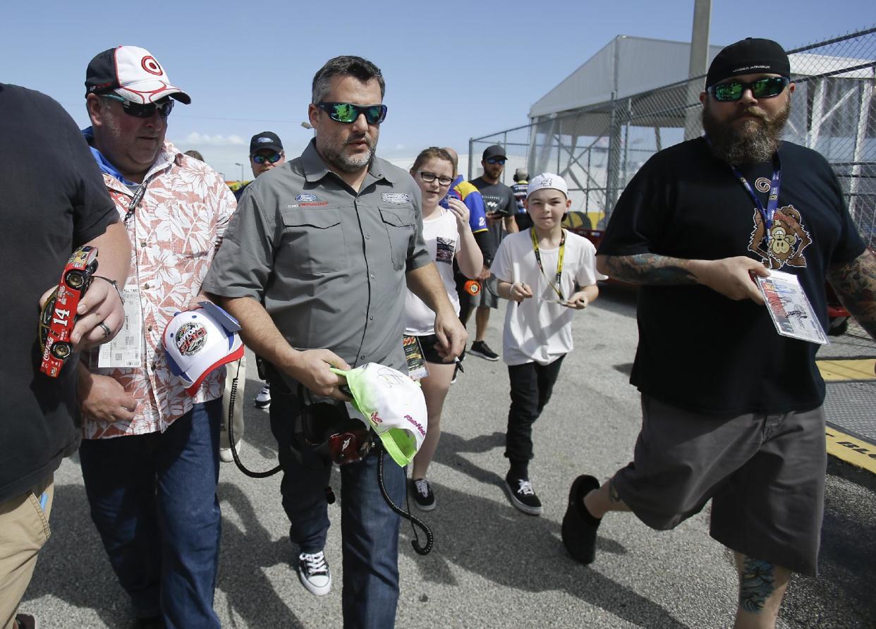 Car owner Tony Stewart, center, is surrounded by fans seeking autographs as he walks through the garages at a NASCAR auto racing practice session at Daytona International Speedway, Friday, Feb. 24, 2017, in Daytona Beach, Fla. (AP Photo/John Raoux)