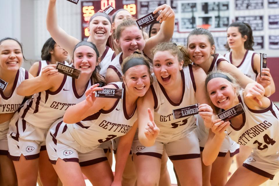 Members of the 2021-2022 Gettysburg girls' basketball team pose for a group photo as they hold up Hershey bars after defeating Lower Dauphin at Gettysburg Area High School on Tuesday, March 1, 2022, in Straban Township. The Warriors won in OT1, 55-43.