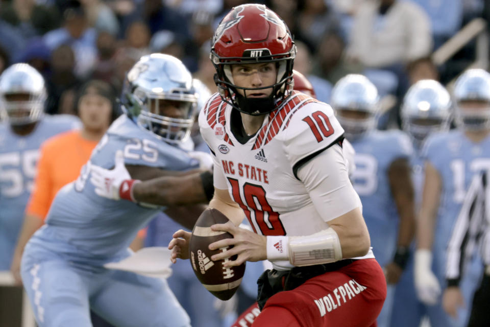 North Carolina State quarterback Ben Finley (10) looks to pitch as North Carolina defensive lineman Kaimon Rucker (25) rushes during the first half of an NCAA college football game Friday, Nov. 25, 2022, in Chapel Hill, N.C. (AP Photo/Chris Seward)