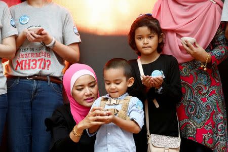Flight attendant who was onboard the missing Malaysia Airlines flight MH370, Mohamad Hazrin Hasnan's wife, Intan, his daughter Iman and son Muhammad hold candles during its fourth annual remembrance event in Kuala Lumpur, Malaysia March 3, 2018. REUTERS/Lai Seng Sin/Files