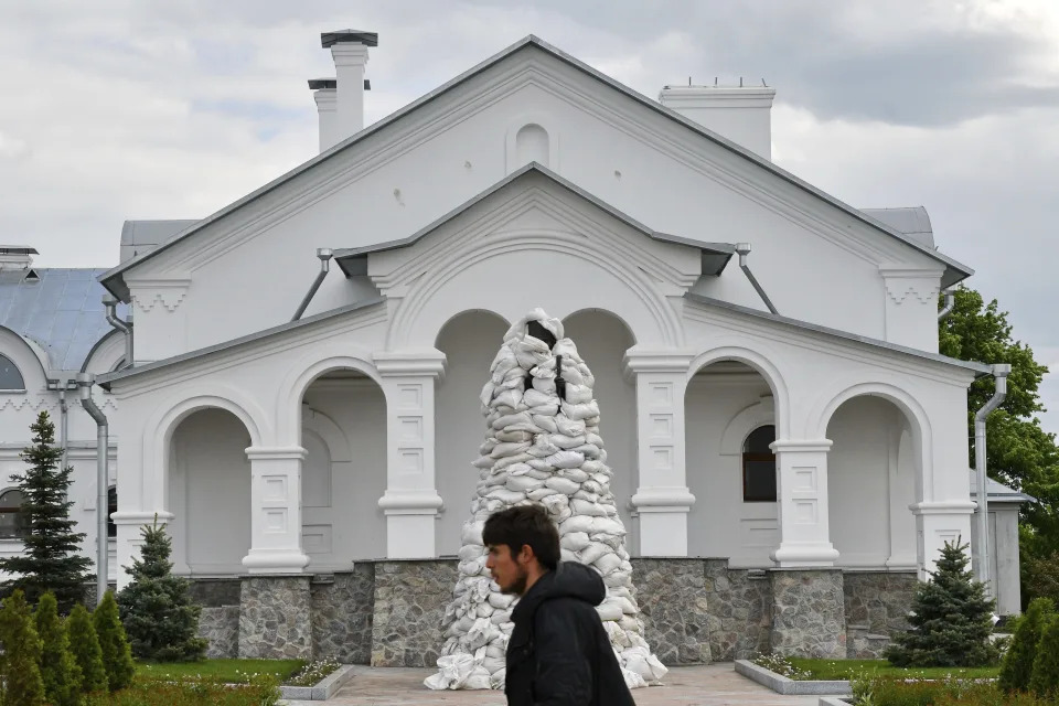 A man walks past the monument of St. John of Shanghai covered with sandbags in a yard the Orthodox Skete in honour of St. John of Shanghai in Adamivka, near Slovyansk, Donetsk region, Ukraine, Tuesday, May 10, 2022. (AP Photo/Andriy Andriyenko)