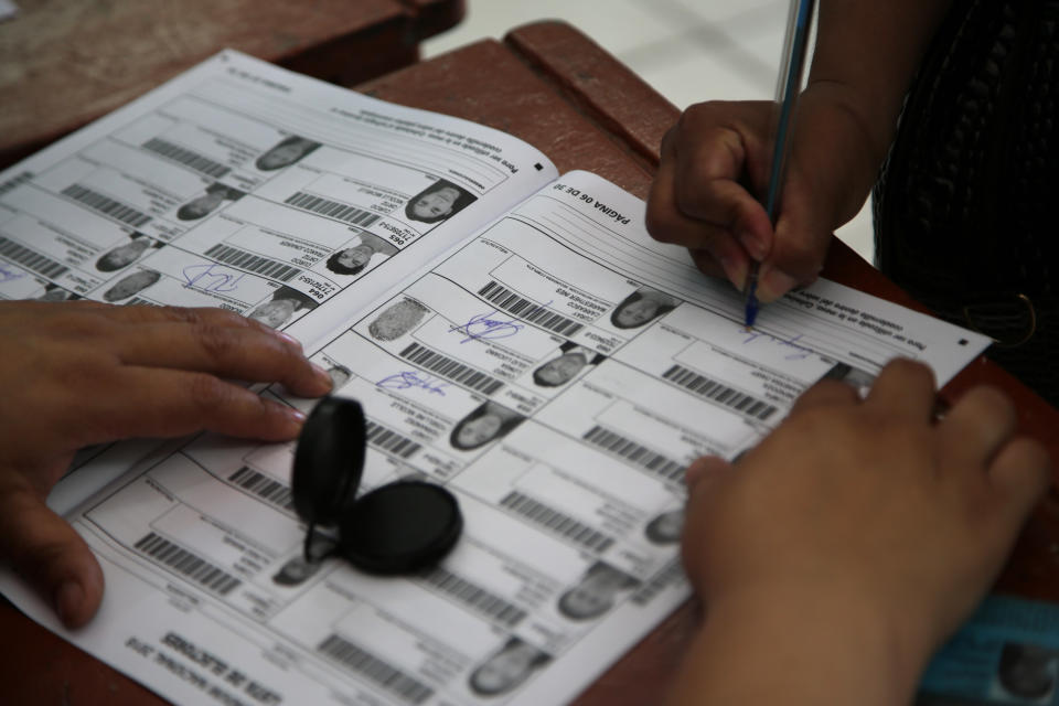 A voter signs her name after having voted in a referendum aimed at curbing corruption in Lima, Peru, Sunday, Dec. 9, 2018. The four questions on the ballot include measures that would prohibit legislators from immediate reelection, create stricter campaign finance rules and reform a scandal-tainted council charged with selecting judges. (AP Photo/Cesar Olmos)