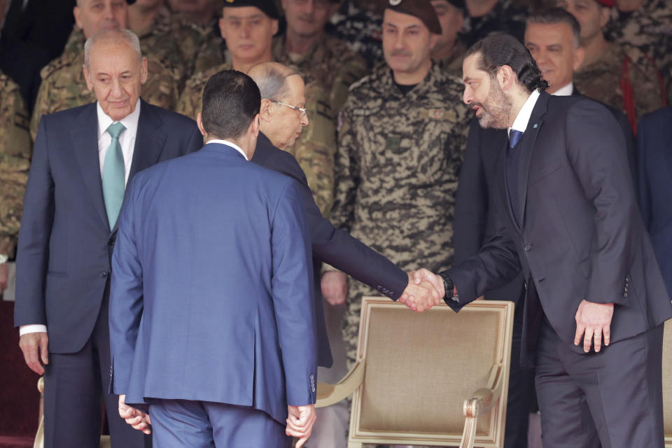 Lebanese President Michel Aoun, center, shakes hands with former Prime Minister Saad Hariri, right, and Parliament Speaker Nabih Berri, before a military parade to mark the 76th anniversary of Lebanon's independence from France at the Lebanese Defense Ministry, in Yarzeh near Beirut, Lebanon, Friday, Nov. 22, 2019. Lebanon's top politicians attended Friday a military parade on the country's 76th Independence Day, appearing for the first time since the government resigned amid nationwide protests now in their second month. (AP Photo/Hassan Ammar)