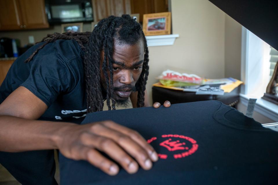 Darryl Harvin, owner of Crooked Crown Apparel, a two-year-old Asbury Park-based provider of modern streetwear, heat presses a logo onto a T-shirt at his brother's home in Eatontown, NJ Thursday, July 7, 2022.