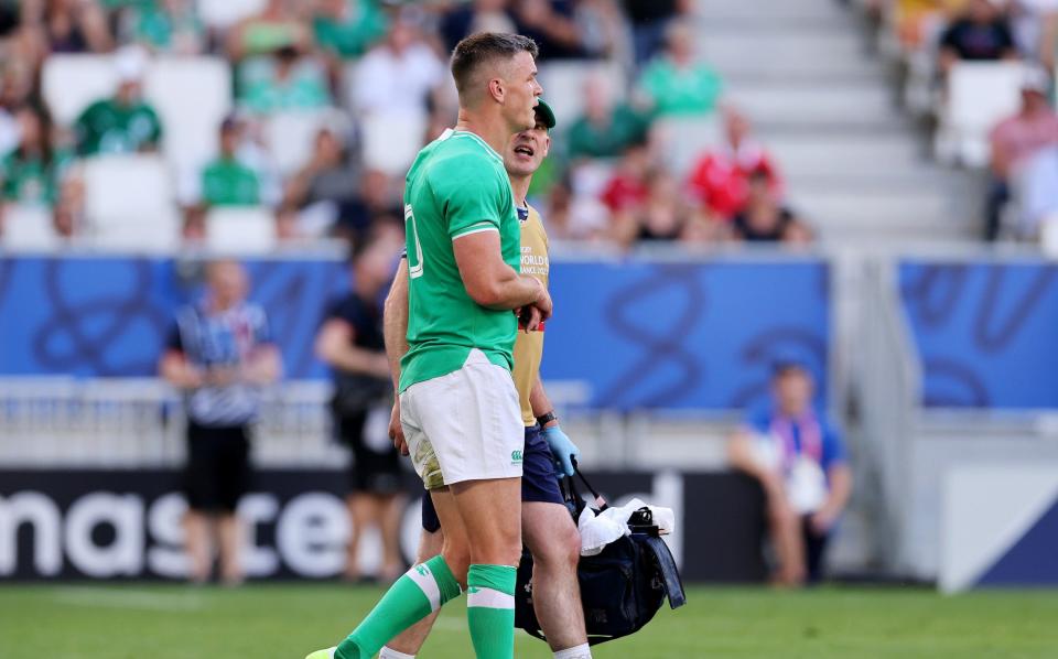 Sexton holds his wrist as he is led off by the physio at half-time