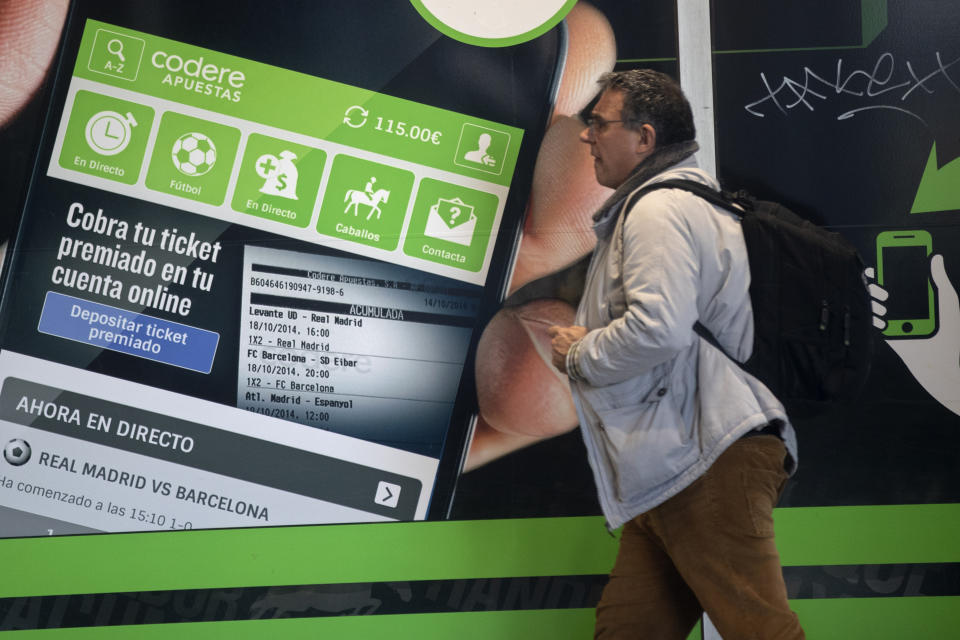 A man walks past an advertisement for online betting on the outside of a betting shop in Madrid, Spain, Friday, Feb. 21, 2020. Spain’s government has announced plans to restrict advertising for on-line betting houses on the Internet, television, and during sporting events. The government said Friday that the law would be the most restrictive in the European Union. (AP Photo/Paul White)