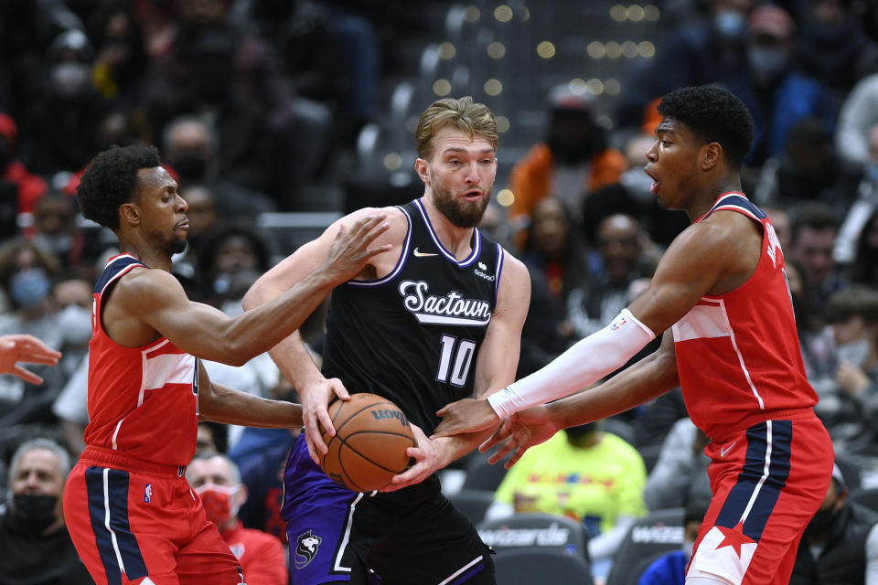 Washington Wizards guard Ish Smith, left, and forward Rui Hachimura, right, pressure Sacramento Kings forward Domantas Sabonis during the first half of an NBA basketball game Saturday, Feb. 12, 2022, in Washington. (AP Photo/Nick Wass)