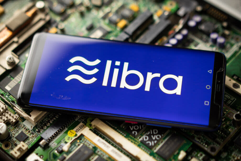 das libra-symbol auf einem smartphone, das auf einem elektronischen technologie-hintergrund liegt