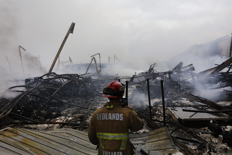 Redlands Fire Capt. Dustin Whitaker surveys damages at a warehouse destroyed in a fire Friday, June 5, 2020, in Redlands, Calif. The fire destroyed the Southern California distribution facility that was used to ship items to Amazon customers but authorities said employees got out and there were no reports of injuries. (AP Photo/Jae C. Hong)