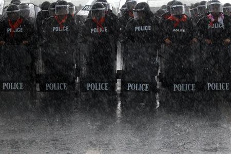 Heavy rain falls on policemen taking positions as rubber farmers protest near the airport in Surat Thani September 4, 2013. REUTERS/Athit Perawongmetha