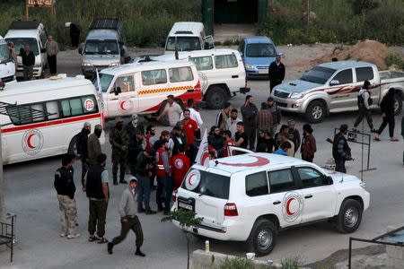 Buses and ambulances evacuating people from four besieged Syrian towns wait at an exchange point supervised by the Syrian Arab Red Crescent, in the town of Qalaat al-Madiq, in Hama province, Syria April 21, 2016. REUTERS/Ammar Abdullah