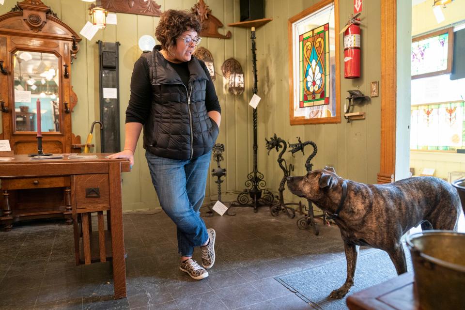 Hannah Manning, 44, of Livonia, a sales associate at Materials Unlimited antique store in Ypsilanti, has a chat with her dog Boss between customers on Sept. 28, 2022. After 50 years, the store will be closing this winter.