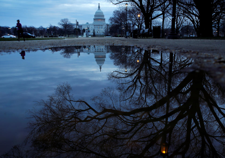 A jogger runs past a reflection of Capitol Hill as a partial U.S. government shutdown continues in Washington, U.S., December 30, 2018.  REUTERS/Jim Young