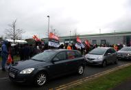 Protestors hold flags as they stop cars during industrial action outside the Amazon warehouse