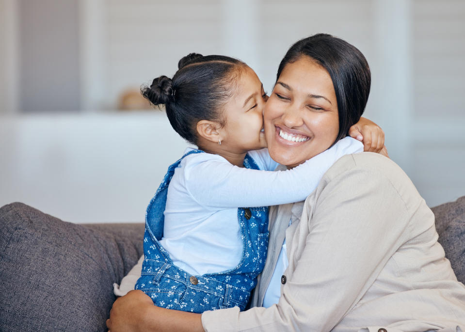 woman and daughter embracing while the daughter kisses the mom on the cheek