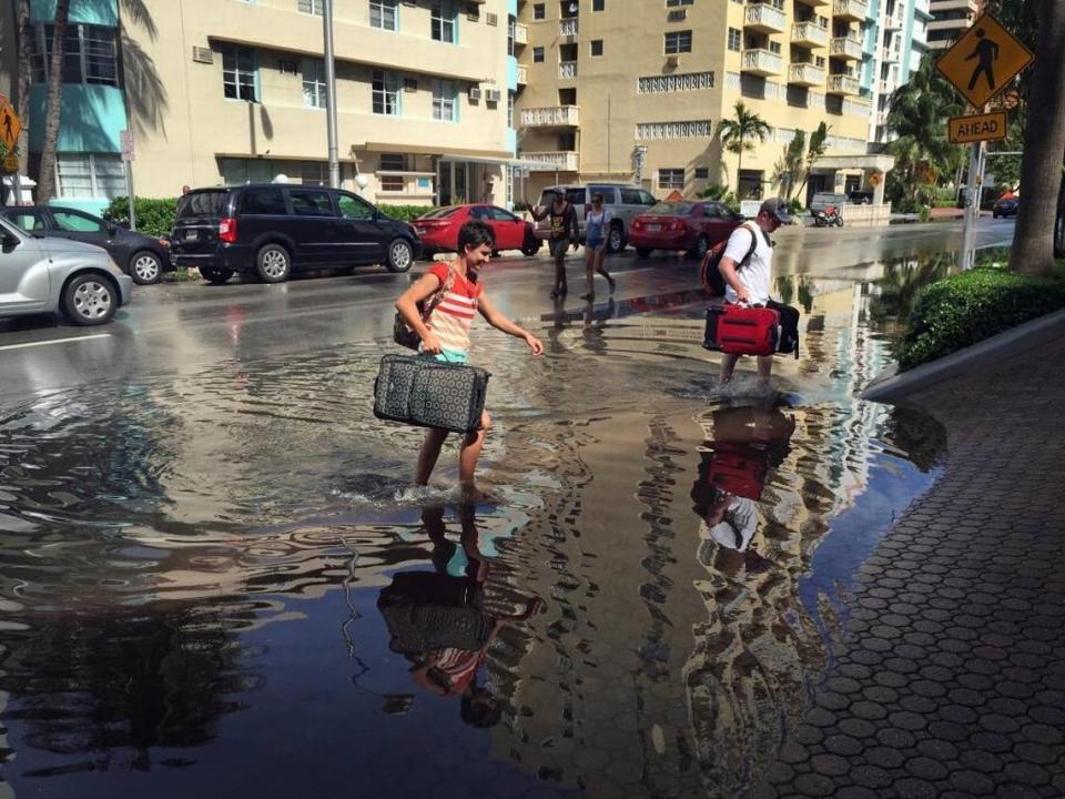 Oakley y Casey Jones, turistas de Idaho Falls, navegan por las calles inundadas de Miami Beach mientras se dirigen a su hotel en Collins Avenue y 30 Street durante una marea alta.