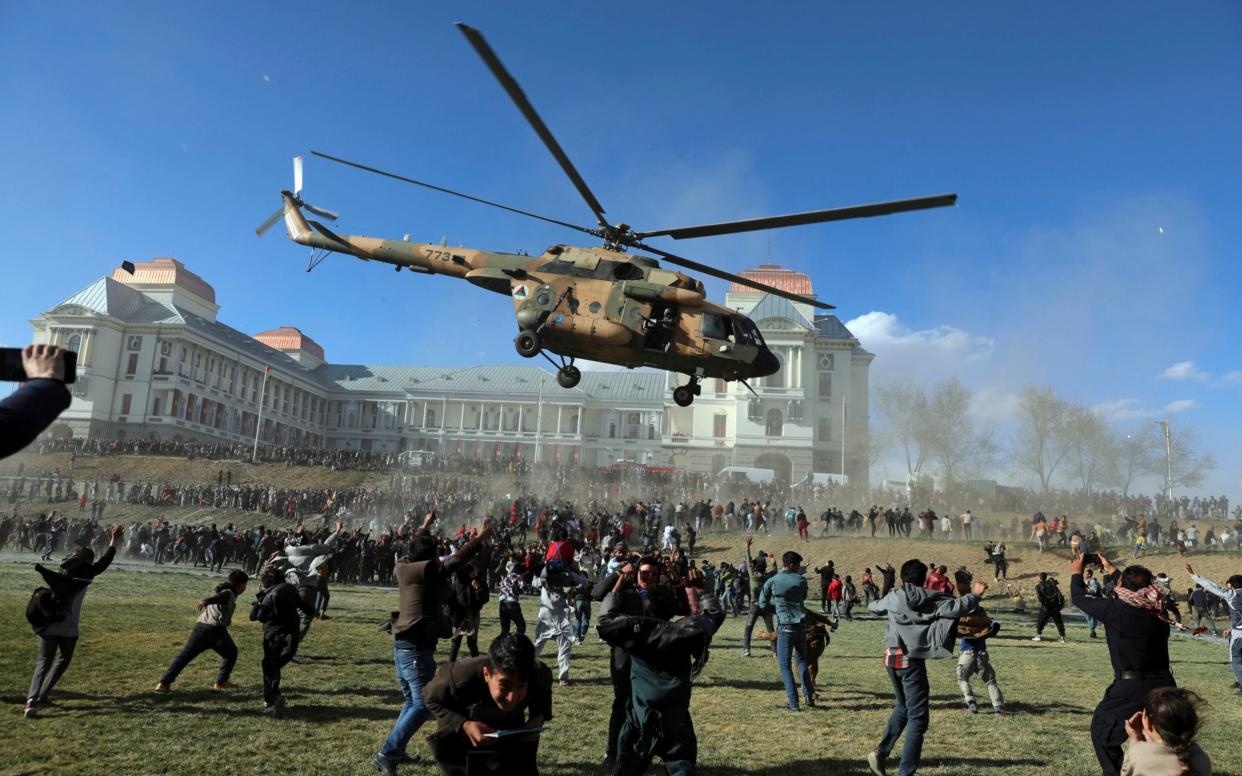 A military helicopter flies over people during the Afghan Security Forces Exhibition, at the Darul Aman Palace in Kabul, Afghanistan, Wednesday, March 3, 2021. The three-day military exhibition in Kabul allowed civilians to have a first hand view and take pictures of weaponry used by Afghan Security forces. (AP Photo/Rahmat Gul)