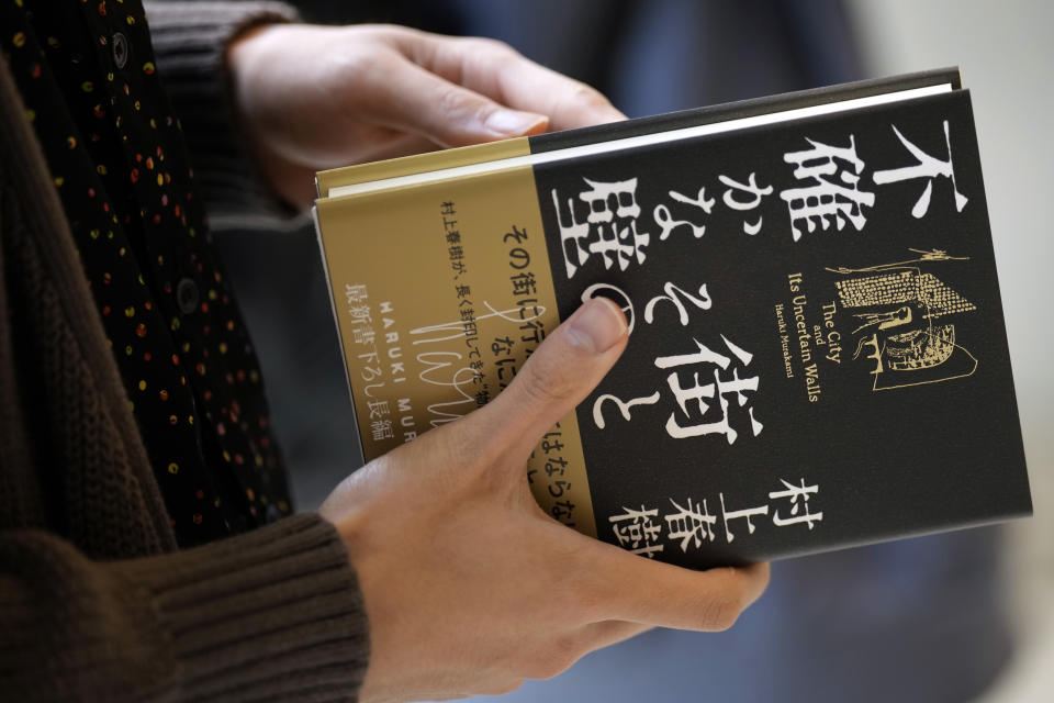 A customer picks up a Japanese writer Haruki Murakami's new novel "The City and Its Uncertain Walls" on the first day for sale at Kinokuniya bookstore in Shinjuku district on early Thursday, April 13, 2023, in Tokyo. Murakami wrote a story of a walled city when he was fresh off his debut. More than four decades later, as a seasoned and acclaimed novelist, he gave it a new life as “The City and Its Uncertain Walls.” (AP Photo/Eugene Hoshiko)