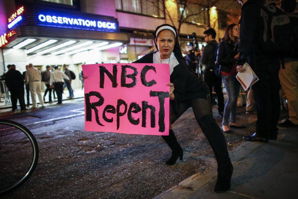 A woman dressed as nun holds a poster as she poses for a photo during a protest in front of NBC studios while they are calling for the network to rescind the invitation to Donald Trump to host Saturday Night Live show on November 4, 2015 in New York. 