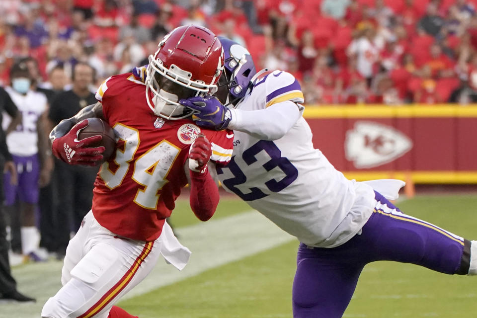 Kansas City Chiefs running back Darwin Thompson (34) runs with the ball as Minnesota Vikings safety Xavier Woods (23) defends during the first half of an NFL football game Friday, Aug. 27, 2021, in Kansas City, Mo. (AP Photo/Charlie Riedel)