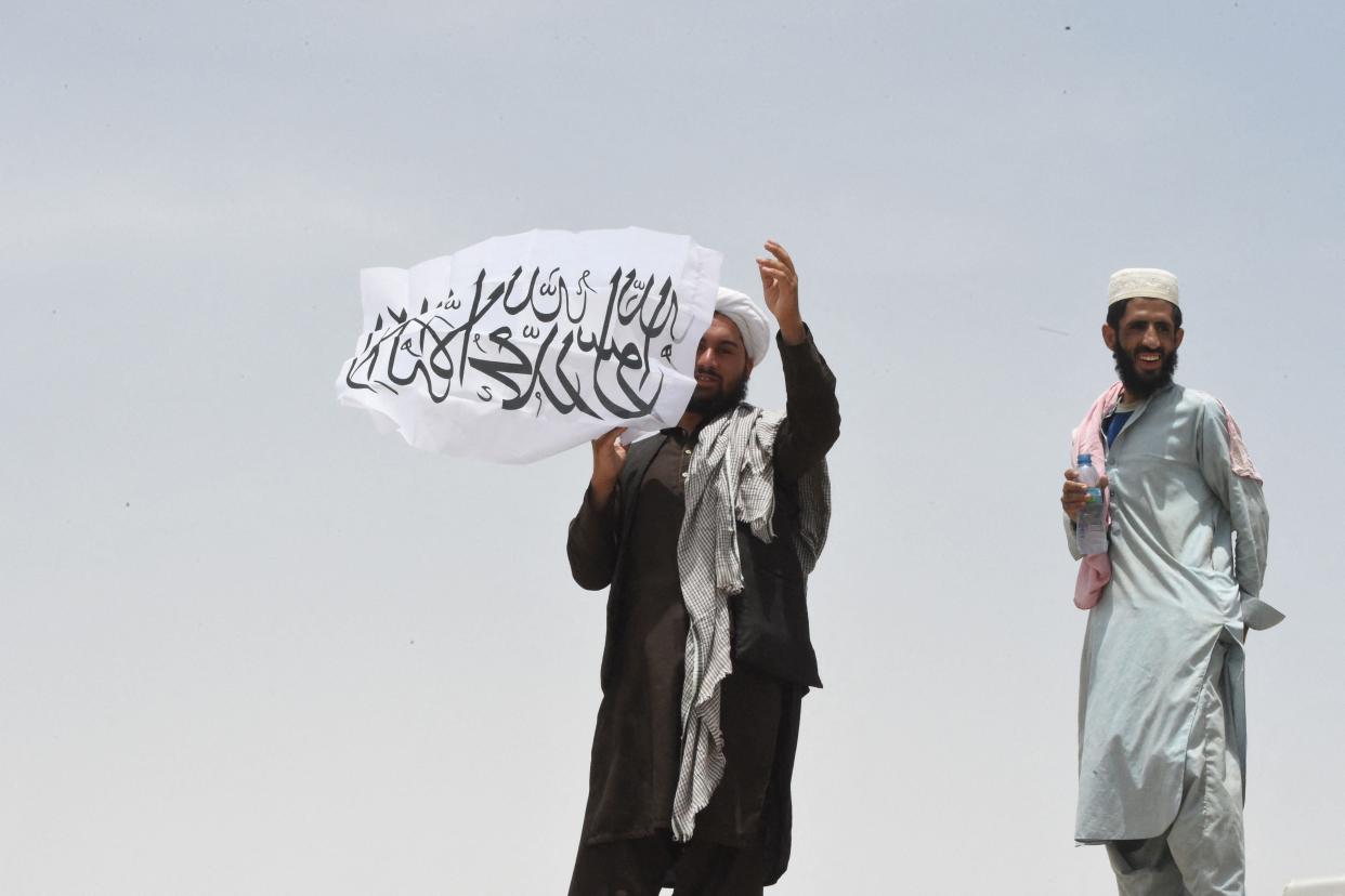  A man standing on the Afghan side of the border holds a Taliban flag near a crossing point in Pakistan (AFP/Getty)