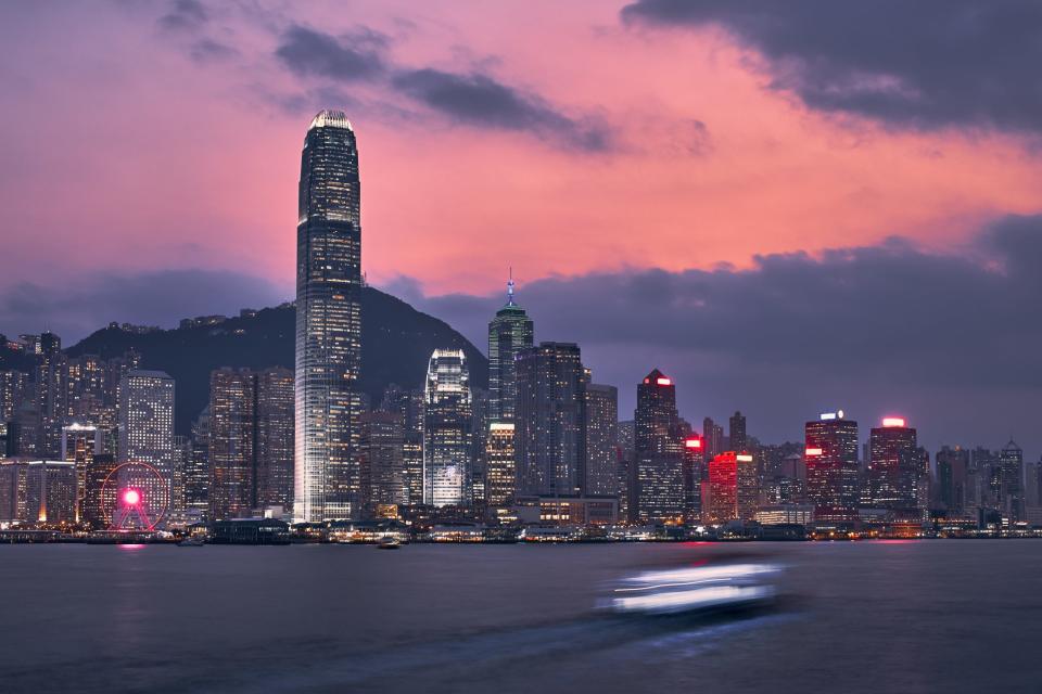 Victoria Harbour and urban skyline with illuminated skyscrapers at dusk, Hong Kong.