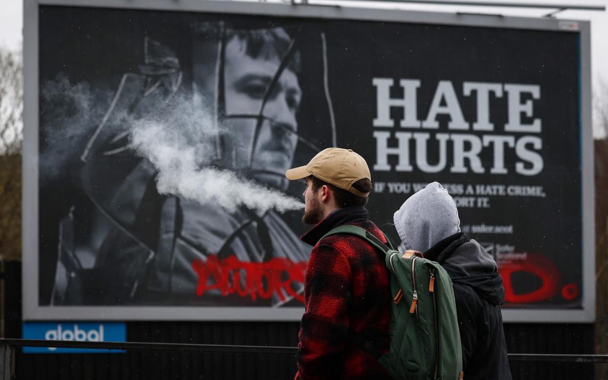 People looking at billboard for Hate Hurts campaign