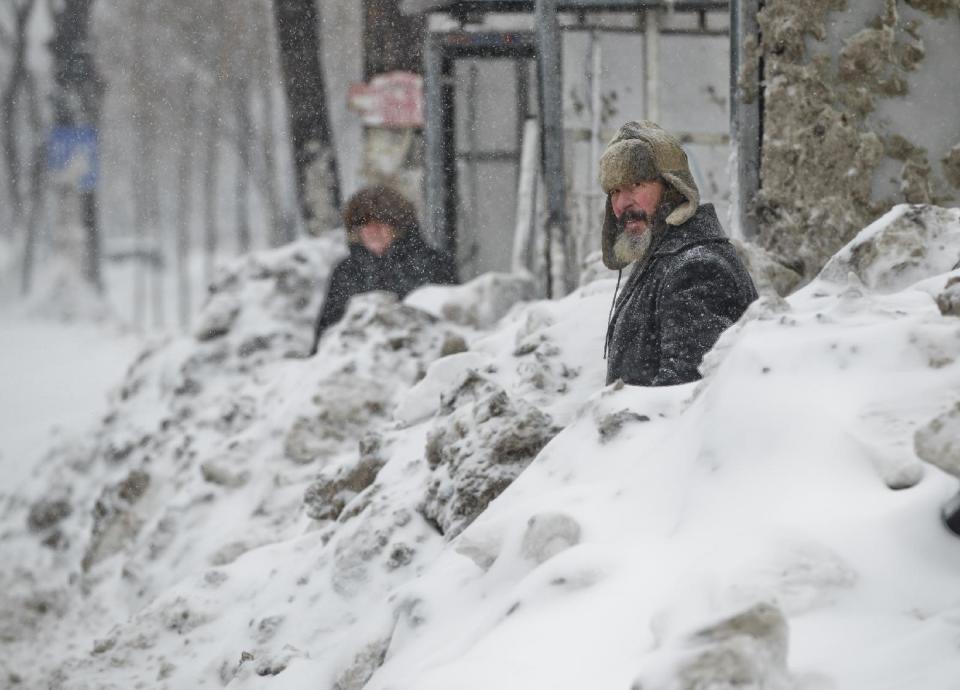 People wait in a snowed in bus stop during a blizzard in Bucharest, Romania, Wednesday, Jan. 29, 2014. Weather forecasters issued a code red severe weather warning as a second wave of blizzards affects the southeastern regions of Romania disrupting road and rail traffic.(AP Photo/Vadim Ghirda)