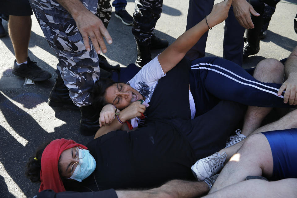Anti-government protesters lie on a road, as they scream and hold onto each other while riot police try to remove them and open the road, in Beirut, Lebanon, Thursday, Oct. 31, 2019. Army units and riot police took down barriers and tents set up in the middle of highways and major intersections Thursday. (AP Photo/Bilal Hussein)