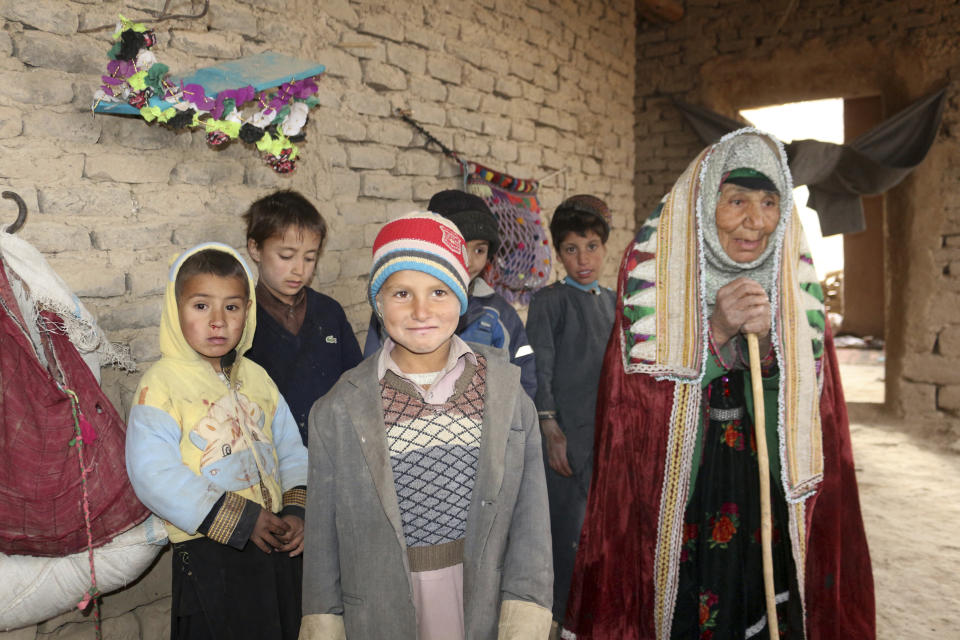 An Afghan family stand inside their home after their home was damaged by Monday's earthquake in the remote western province of Badghis, Afghanistan, Tuesday, Jan. 18, 2022. The United Nations on Tuesday raised the death toll from Monday's twin earthquakes in western Afghanistan, saying three villages of around 800 houses were flattened by the temblors. (Abdul Raziq Saddiqi)