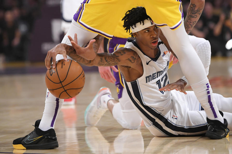 Memphis Grizzlies guard Ja Morant, below, tries to pass the ball from under the legs of Los Angeles Lakers forward Anthony Davis during the first half of an NBA basketball game Friday, Feb. 21, 2020, in Los Angeles. (AP Photo/Mark J. Terrill)