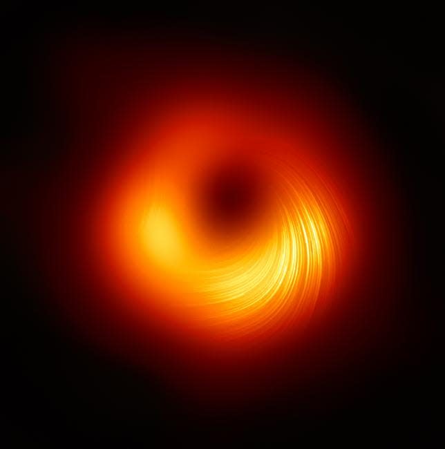 black hole image shows a glowing red disk with its lower half bright yellow full of streaks arcing outward