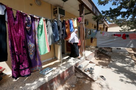 A displaced Libyan woman who fled after clashes, walks at a shut-down factory used as a shelter in Tajura neighborhood, east of Tripoli