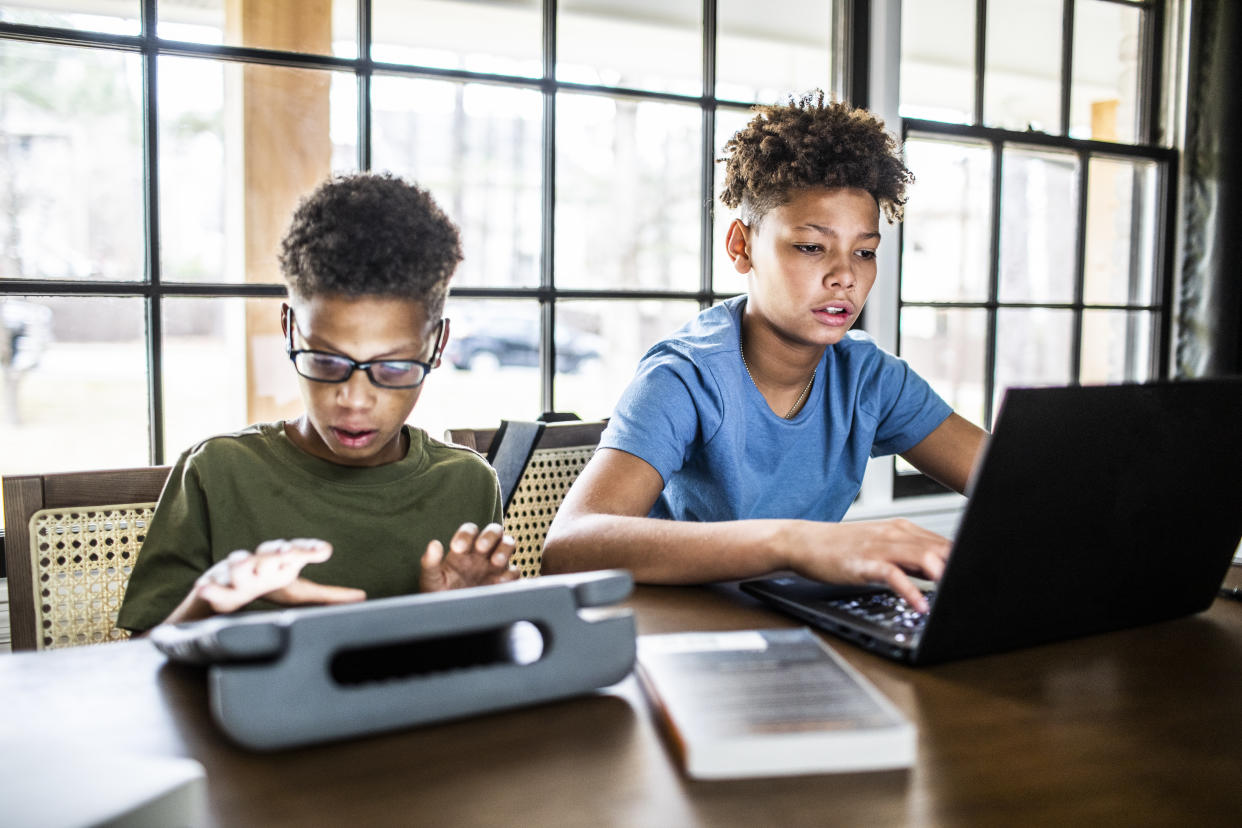 Boys using tablets and laptops in kitchen