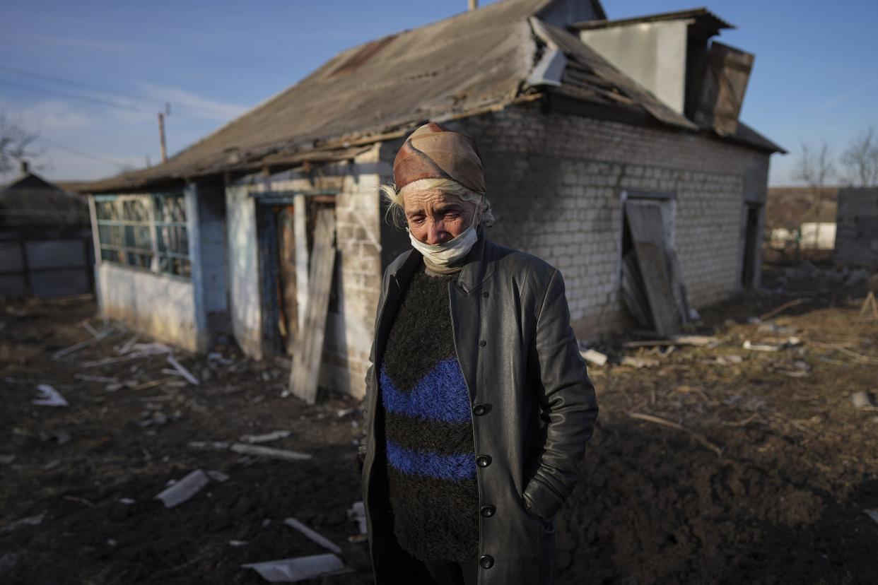 Tetyana Tomenko, a local resident, cries standing in front of her damaged house after alleged shelling by separatists forces in Novognativka, eastern Ukraine, Sunday, Feb. 20, 2022. Russia is extending military drills near Ukraine's northern borders after two days of sustained shelling along the contact line between Ukrainian soldiers and Russia-backed separatists in eastern Ukraine. The exercises in Belarus, which borders Ukraine to the north, originally were set to end on Sunday.