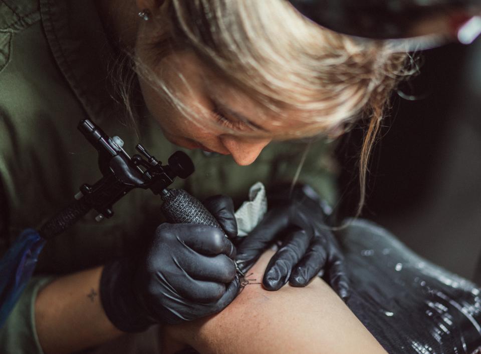 woman tattoo a client's arm