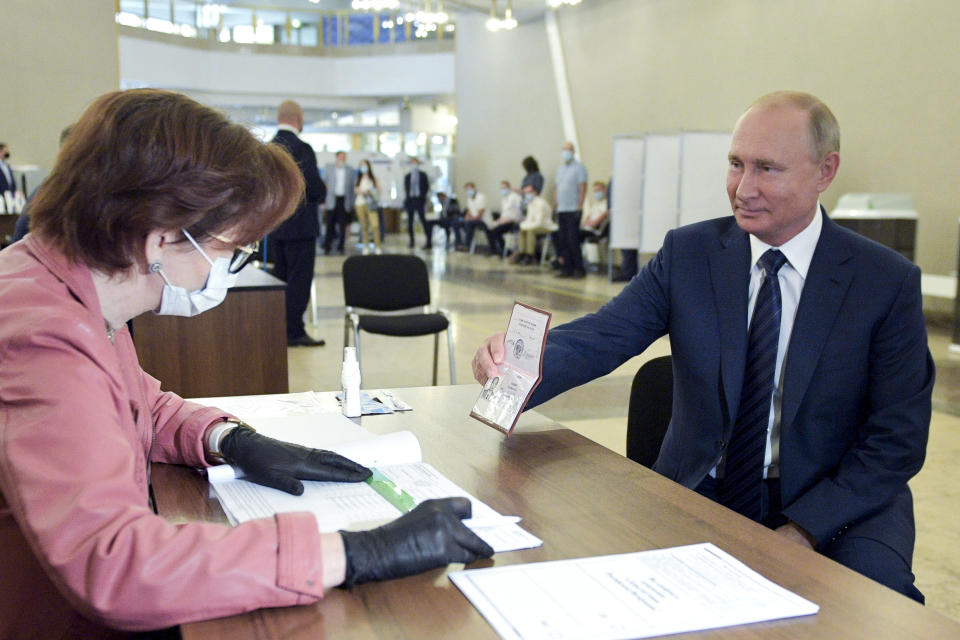 El presidente ruso Vladimir Putin muestra su pasaporte a una trabajadora electoral poco antes de votar el miércoles 1 de julio de 2020, en Moscú. (Alexei Druzhinin, Sputnik, fotografía del Pool del Kremlin vía AP)