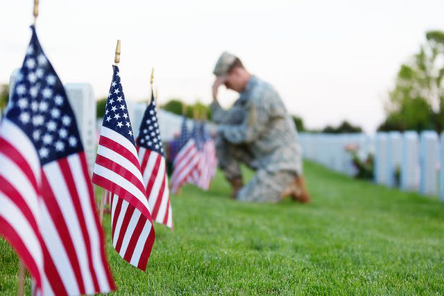 <p>Getty</p> A stock photo of a solider kneeling at a veteran's grave