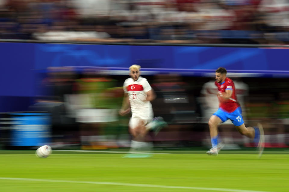 In this image taken with a slow shutter speed, Turkey's Baris Alper Yilmaz (21) runs ahead of Czech Republic's David Jurasek during a Group F match between Czech Republic and Turkey at the Euro 2024 soccer tournament in Hamburg, Germany, Wednesday, June 26, 2024. (AP Photo/Petr David Josek)